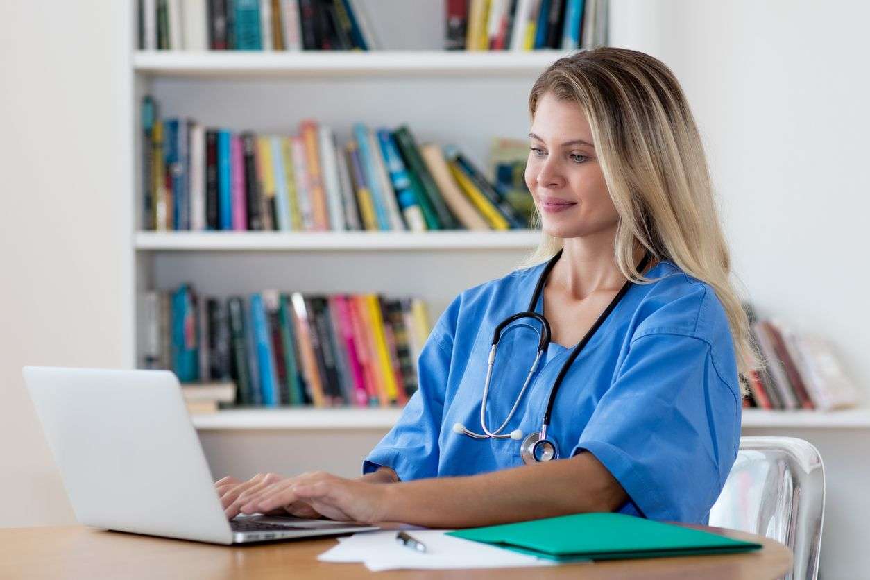 Beautiful blond nurse working at computer at hospital