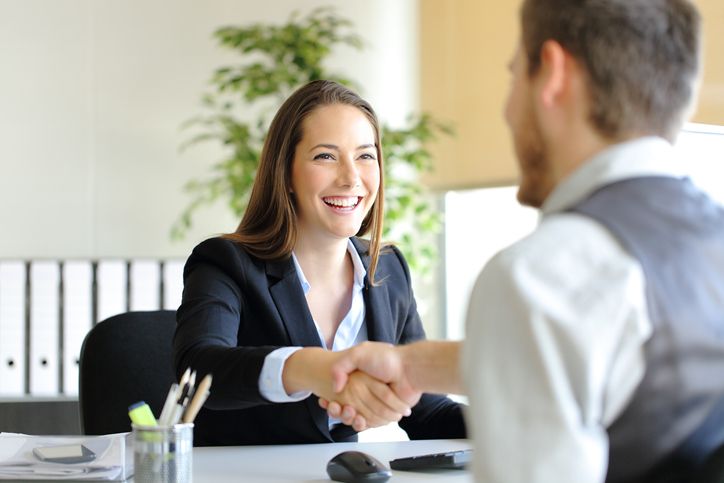 Smiling professionals shaking hands during a medical office specialist career interview.